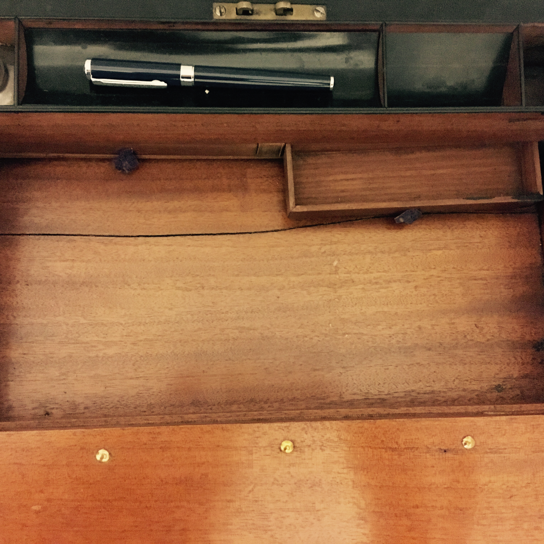 The interior of an antique writing slope, with one small secret drawer pulled open.